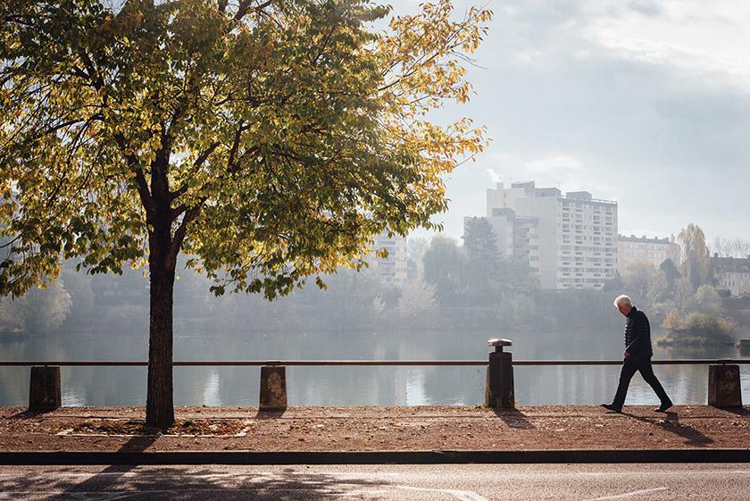 photo of elderly man waking by a river