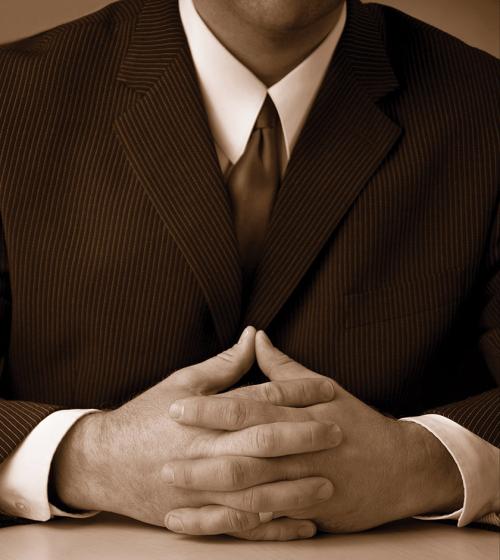 man sitting at a table with hands clasped