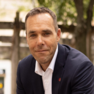 Michael Hironimus, a middle aged caucasian male in a blue suit coat and white collared shirt.