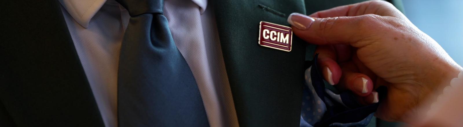 Woman pinning CCIM Designation Pin on Man's Lapel