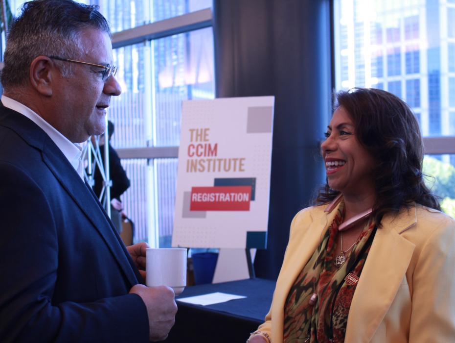 Two CCIMs, a man and a woman, network at an event.