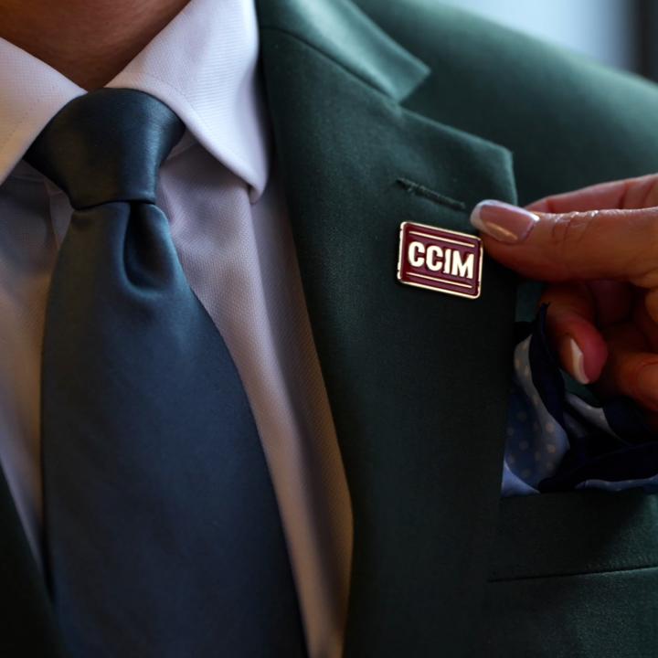 Woman pinning CCIM Designation Pin on Man's Lapel