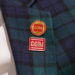 Close-up of a plaid blazer with two CCIM pins.
