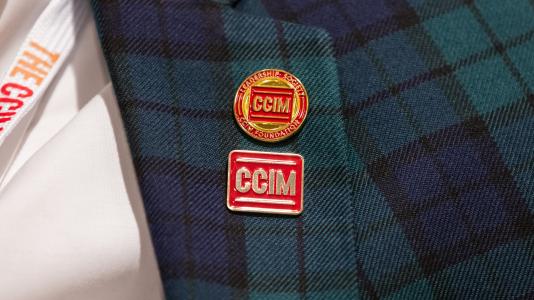 Close-up of a plaid blazer with two CCIM pins.